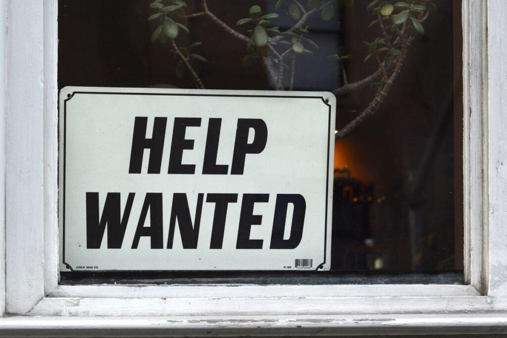 Help wanted sign in window with plant in background